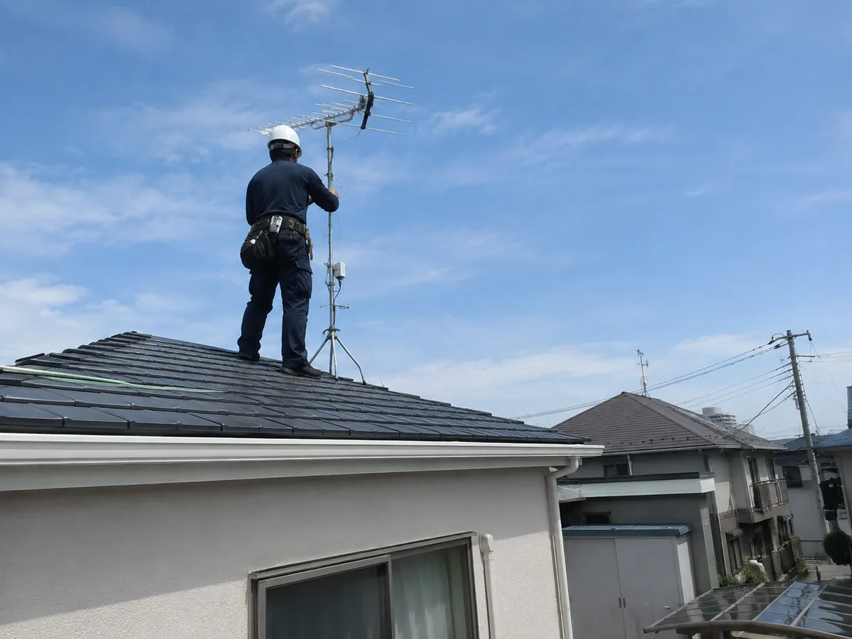 住宅の屋根でテレビアンテナを設置する作業