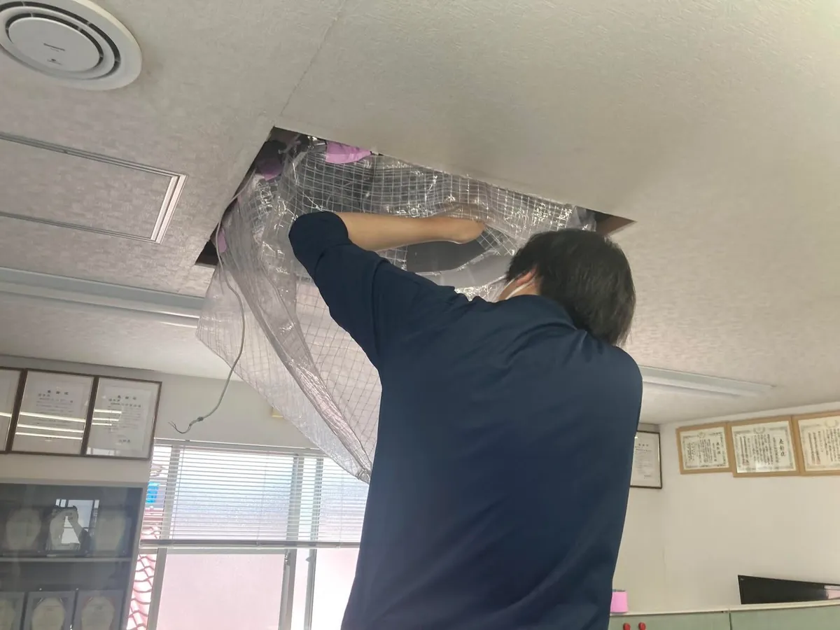 天井の空調設備を養生する作業